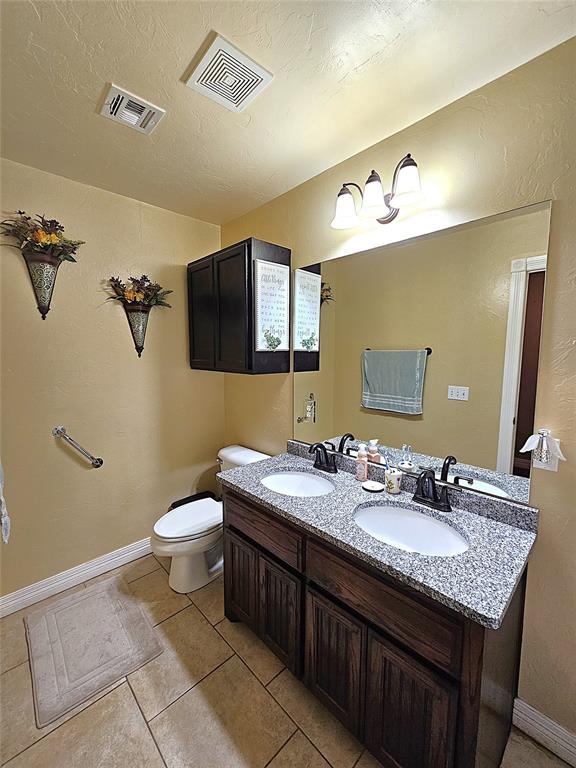 bathroom with toilet, visible vents, and a sink