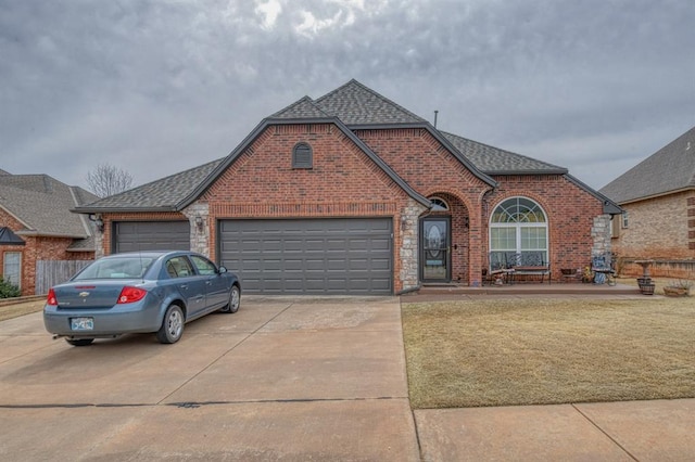 view of front of property with an attached garage, roof with shingles, concrete driveway, and brick siding