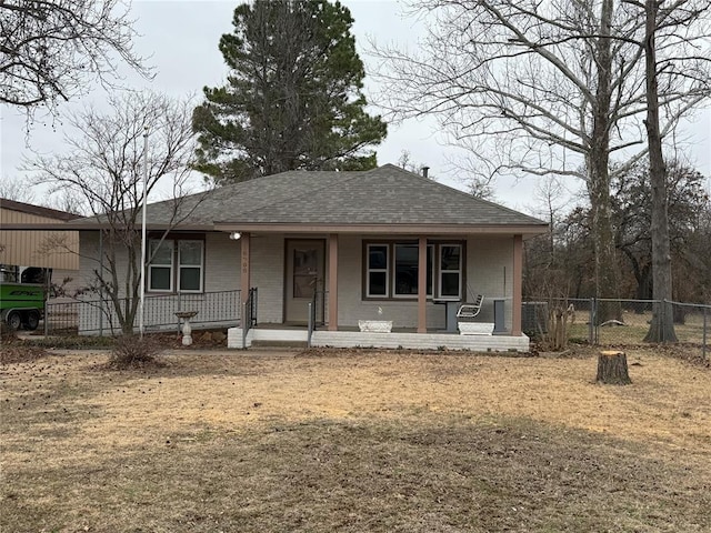 view of front of property with covered porch, a shingled roof, and fence