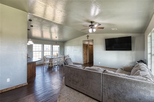 living room featuring visible vents, baseboards, lofted ceiling, dark wood-type flooring, and ceiling fan with notable chandelier