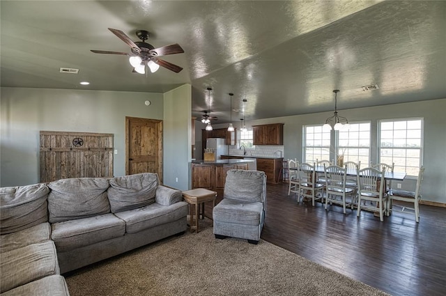 living area with dark wood-style floors, ceiling fan, and visible vents