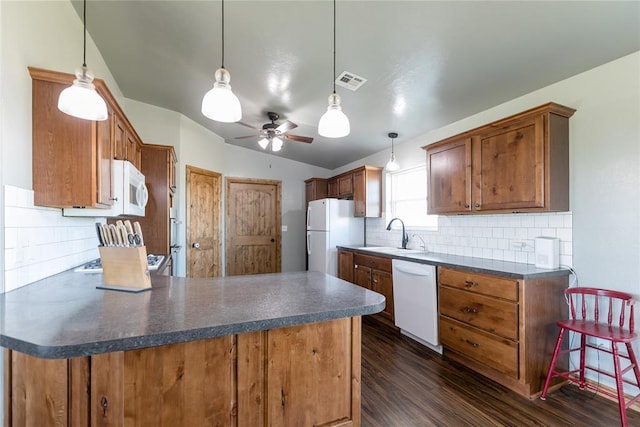 kitchen featuring dark wood-style floors, dark countertops, white appliances, and a sink