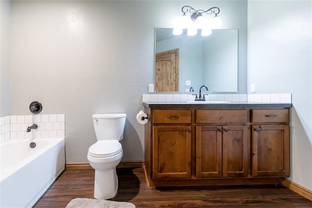 full bath with baseboards, toilet, wood finished floors, a garden tub, and vanity