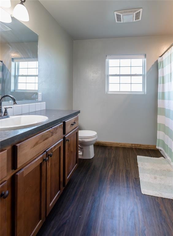 bathroom with a healthy amount of sunlight, visible vents, toilet, and wood finished floors