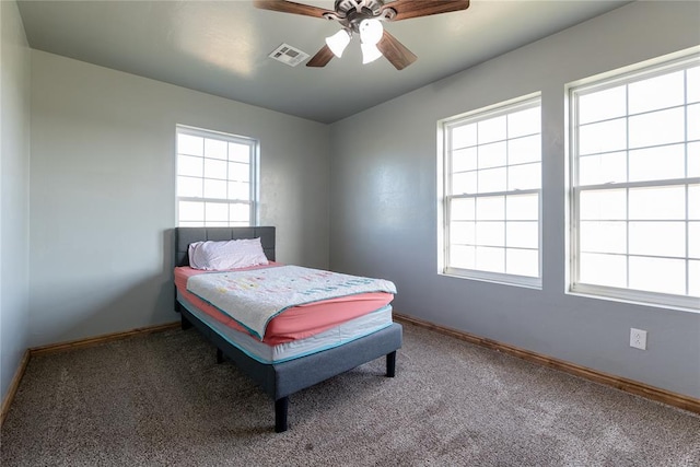 carpeted bedroom featuring a ceiling fan, visible vents, and baseboards