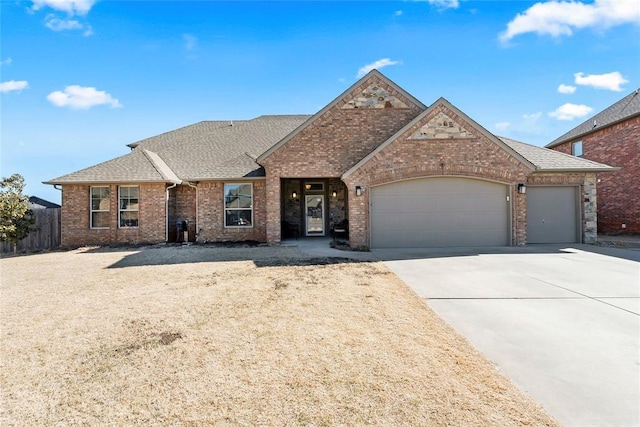 view of front of property with driveway, roof with shingles, an attached garage, fence, and brick siding