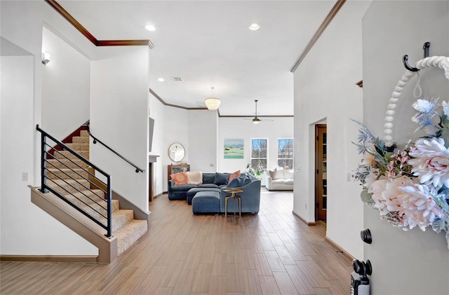 living room featuring stairs, ornamental molding, wood finished floors, and recessed lighting