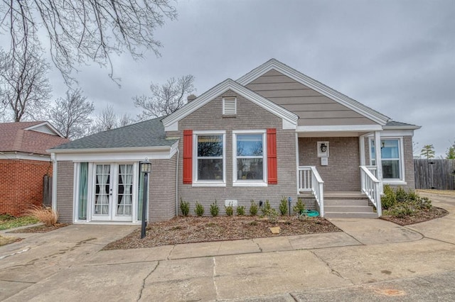 view of front of house featuring french doors, brick siding, and fence