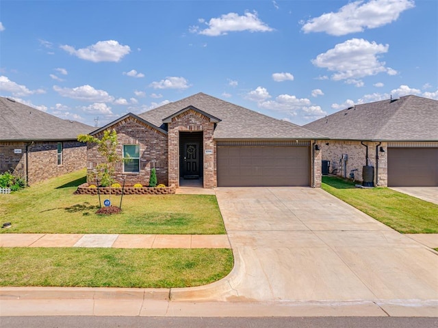 4200 Palmetto Bluff Dr, Mustang, OK 73064 - view of front of home with an attached garage, brick siding, concrete driveway, roof with shingles, and a front yard