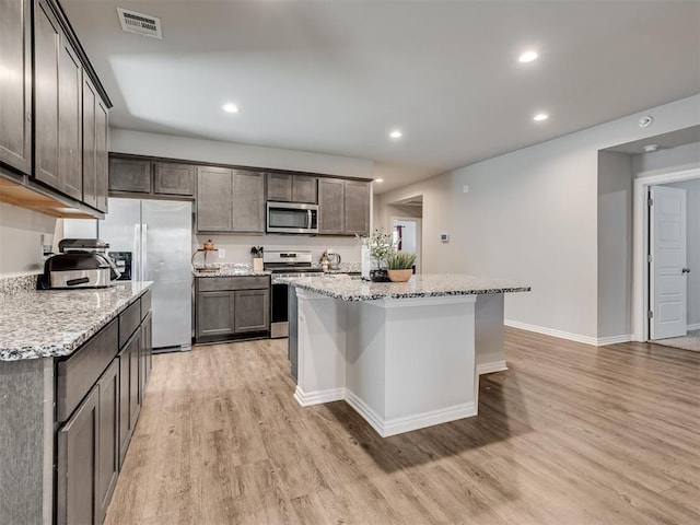 kitchen with light stone counters, recessed lighting, visible vents, appliances with stainless steel finishes, and light wood-style floors