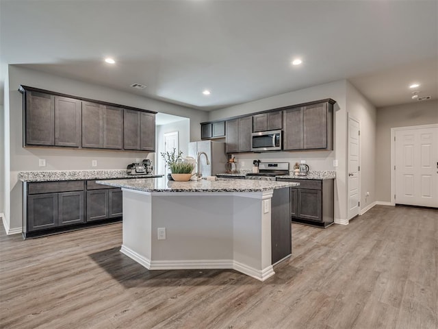 kitchen with stainless steel appliances, light wood-type flooring, light stone counters, and recessed lighting