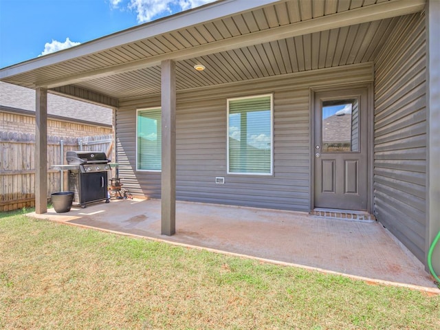 doorway to property with a patio area, fence, and a yard