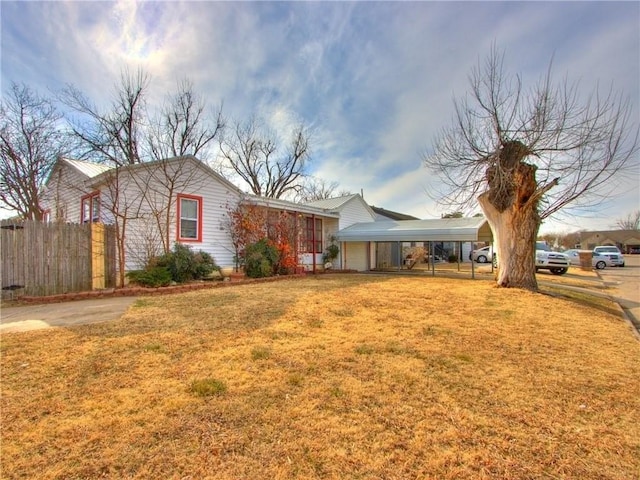 exterior space featuring a carport, a front yard, and fence