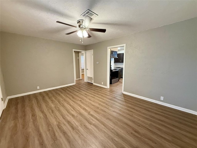 unfurnished bedroom featuring baseboards, a textured ceiling, visible vents, and wood finished floors