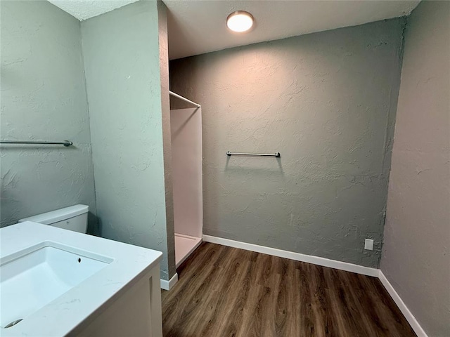 bathroom featuring baseboards, wood finished floors, and a textured wall