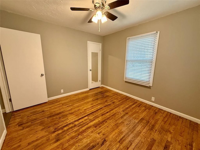 unfurnished room featuring ceiling fan, a textured ceiling, baseboards, and wood finished floors