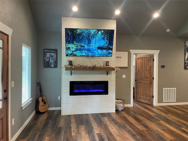 unfurnished living room with wood finished floors, a glass covered fireplace, visible vents, and baseboards