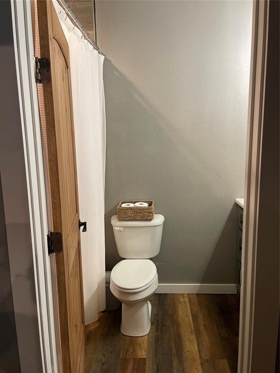 full bath with baseboards, vanity, toilet, and wood finished floors