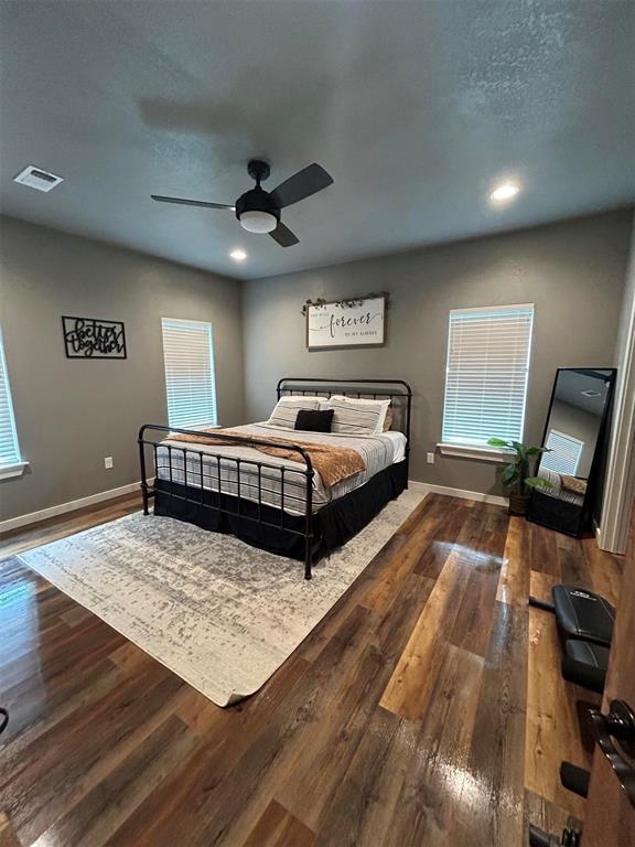 bedroom featuring visible vents, baseboards, and wood finished floors