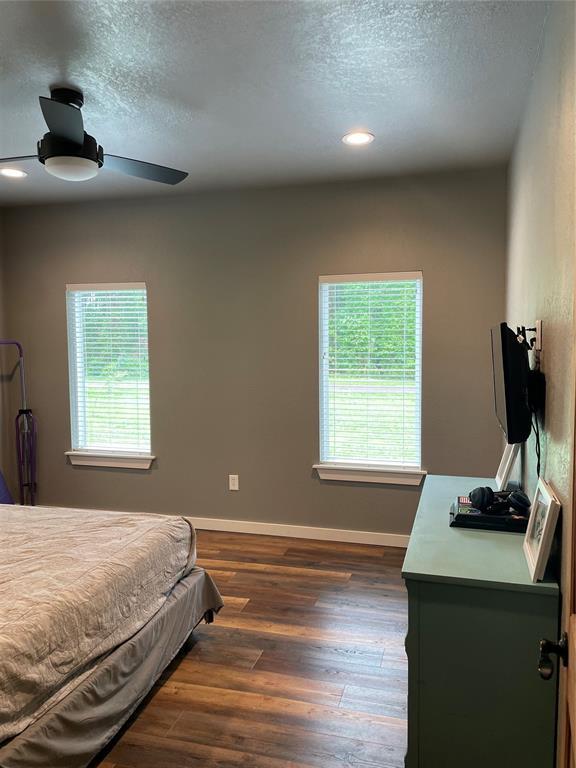 bedroom featuring a ceiling fan, a textured ceiling, baseboards, and dark wood-style flooring