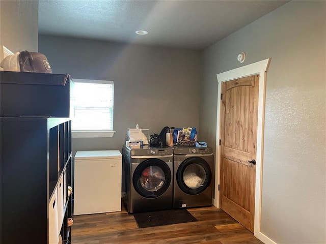 clothes washing area featuring laundry area, washing machine and dryer, and dark wood-type flooring