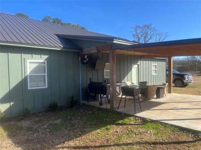 exterior space with board and batten siding, a patio area, and metal roof