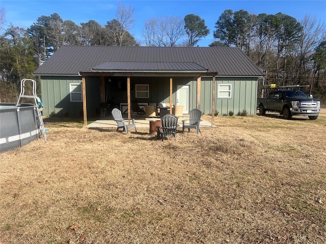 rear view of property featuring a fire pit, metal roof, board and batten siding, and a patio