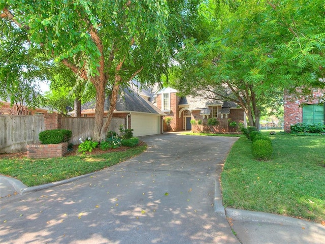 view of front of house with aphalt driveway, an attached garage, brick siding, fence, and a front lawn