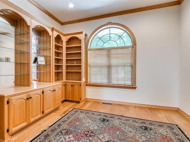 unfurnished office featuring baseboards, light wood-type flooring, visible vents, and crown molding