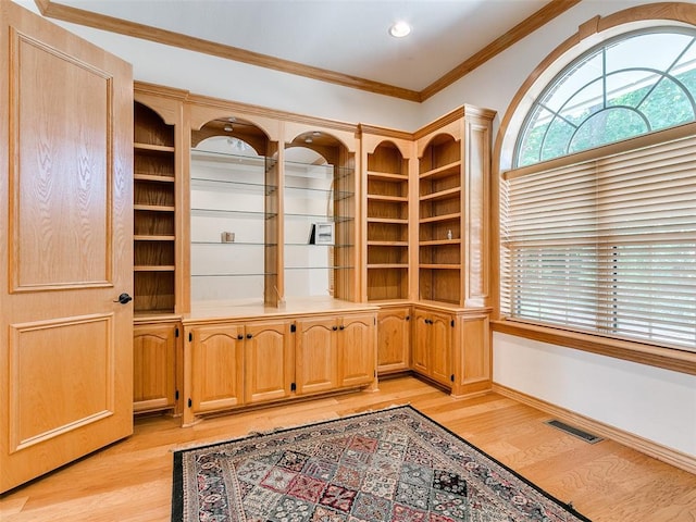 unfurnished office featuring light wood finished floors, baseboards, visible vents, and ornamental molding