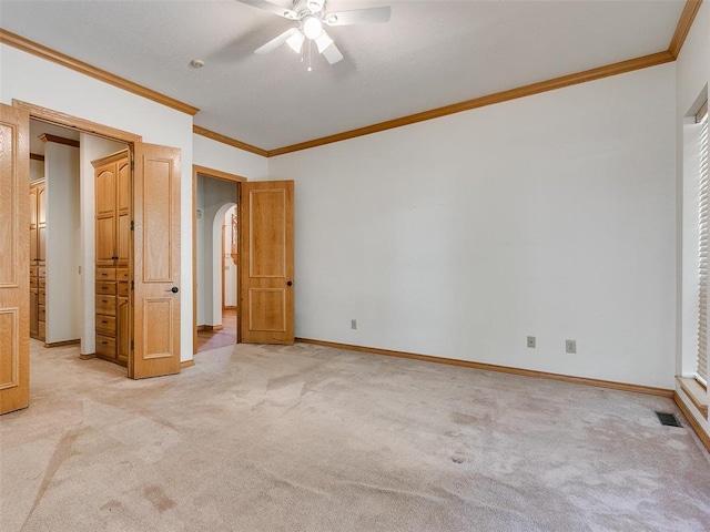 unfurnished bedroom with light carpet, baseboards, visible vents, arched walkways, and crown molding