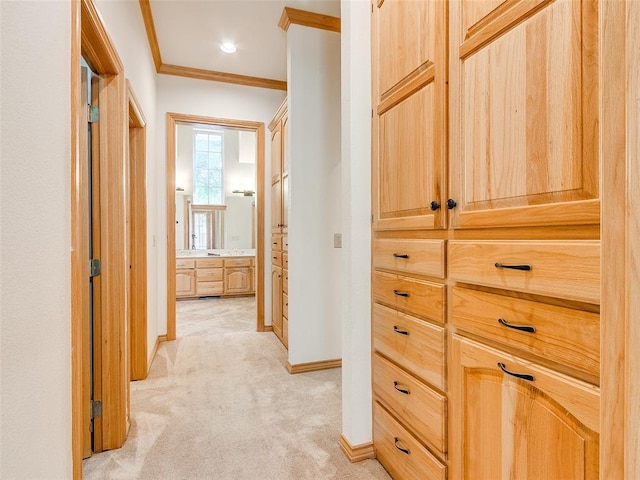 corridor featuring baseboards, ornamental molding, and light colored carpet