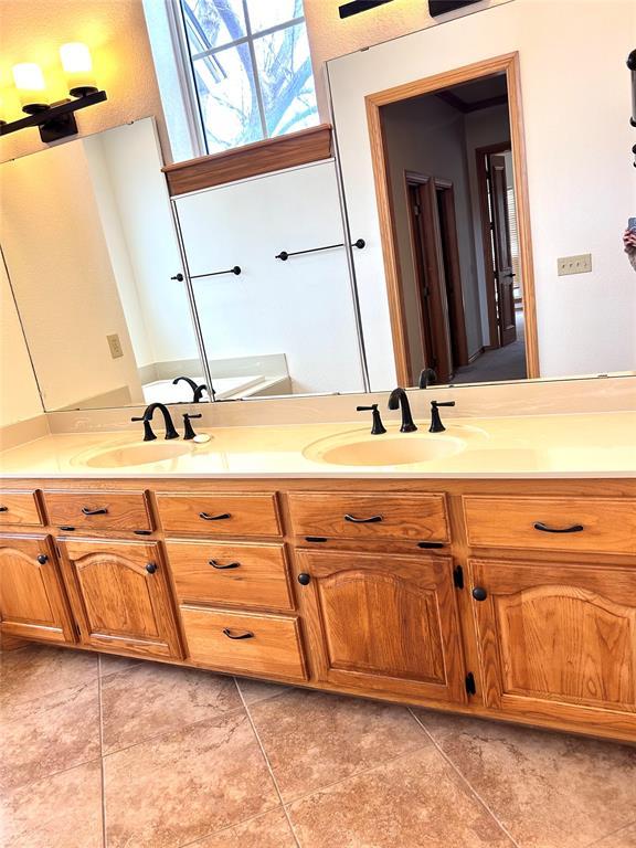 full bath with double vanity, tile patterned flooring, and a sink