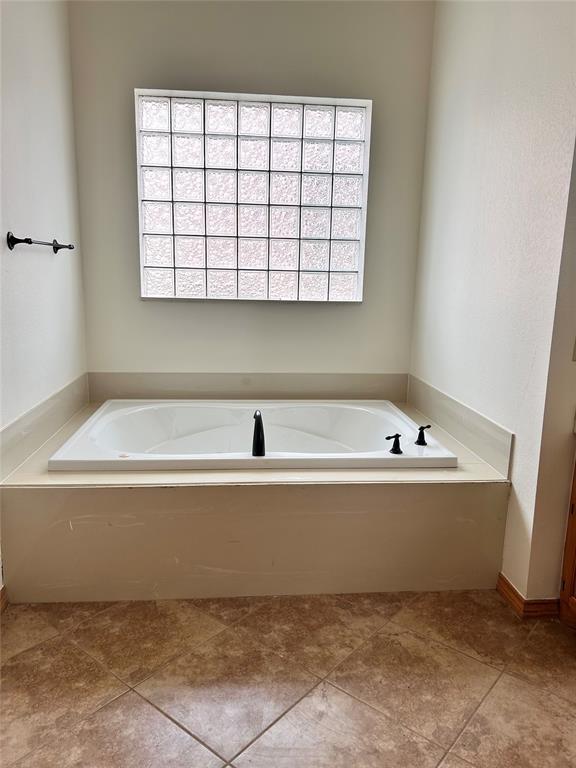 bathroom with tile patterned floors, a garden tub, and a healthy amount of sunlight