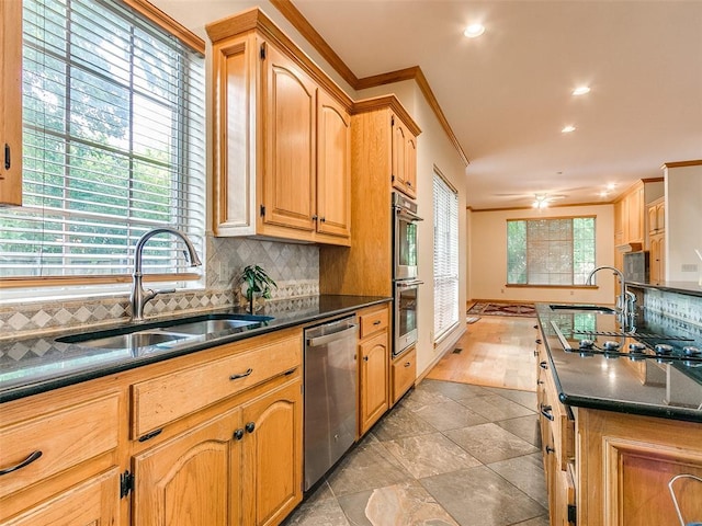 kitchen with stainless steel appliances, dark countertops, crown molding, and a sink