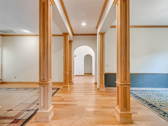 interior space featuring light wood finished floors, decorative columns, and arched walkways