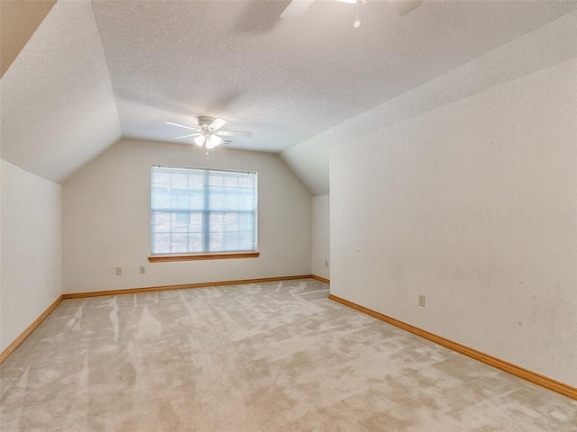 bonus room with carpet, lofted ceiling, ceiling fan, a textured ceiling, and baseboards