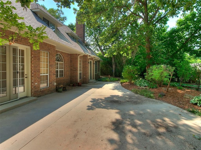 view of side of home with a chimney, concrete driveway, and brick siding