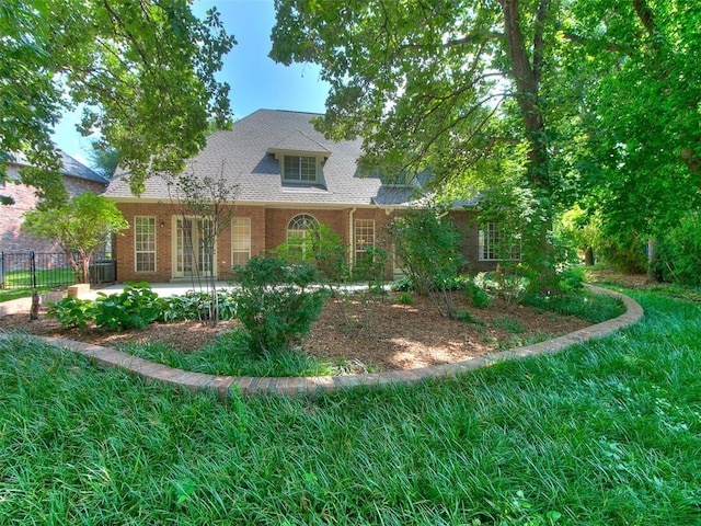 view of front of home featuring a patio, brick siding, a shingled roof, and fence