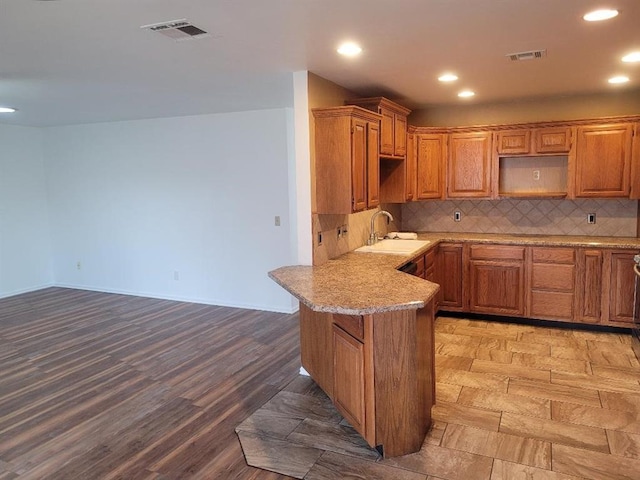 kitchen with tasteful backsplash, visible vents, a sink, and a peninsula