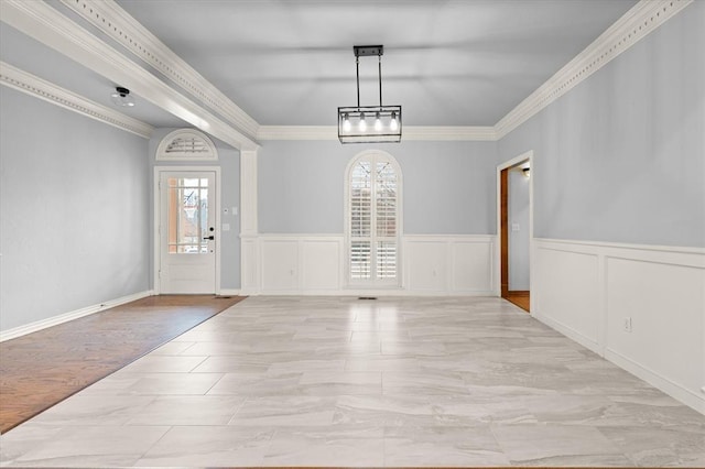 foyer entrance featuring a wainscoted wall, ornamental molding, and a wealth of natural light