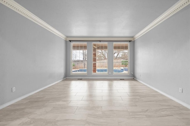 empty room featuring baseboards and crown molding