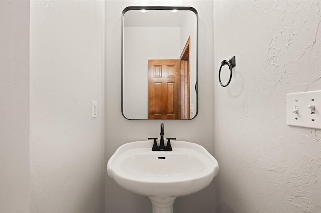 bathroom featuring a textured wall and a sink