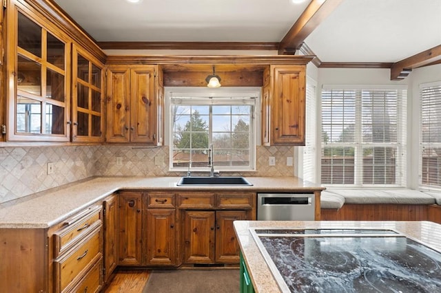 kitchen with brown cabinets, a sink, beamed ceiling, and stainless steel dishwasher