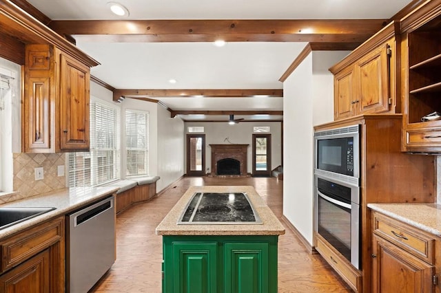 kitchen featuring beam ceiling, a fireplace, open shelves, appliances with stainless steel finishes, and open floor plan