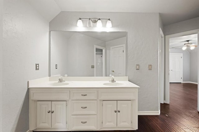 full bathroom featuring a textured wall, double vanity, wood finished floors, and a sink