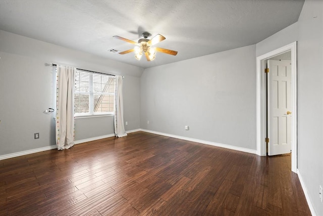 spare room featuring a ceiling fan, visible vents, baseboards, and wood finished floors