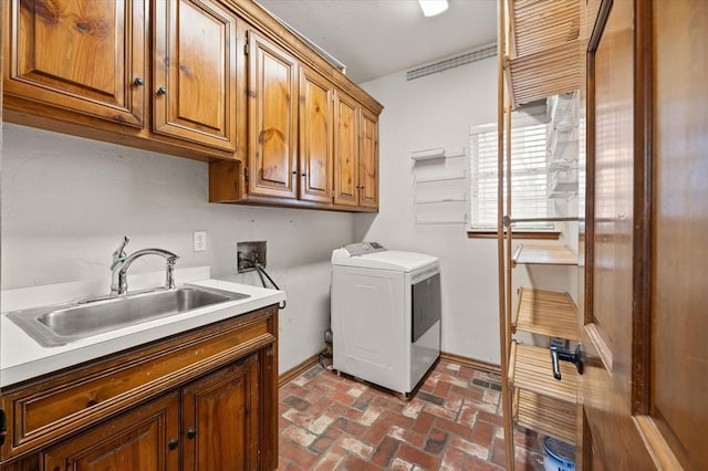 laundry room with brick floor, washer hookup, cabinet space, a sink, and baseboards