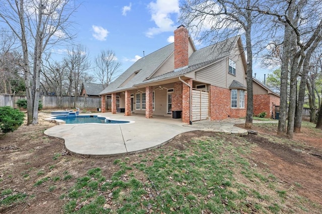 back of property featuring brick siding, a chimney, fence, and a patio