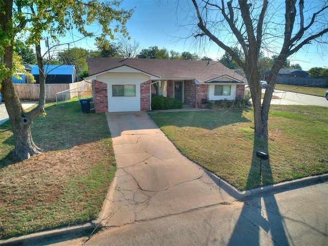 view of front of property with driveway, roof with shingles, fence, a front lawn, and brick siding